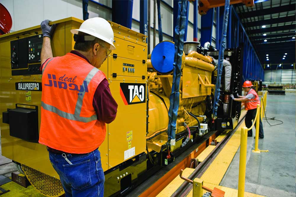 کارگران در حال نصب ژنراتور گاز کاترپیلار در یک سایت ساختمانی